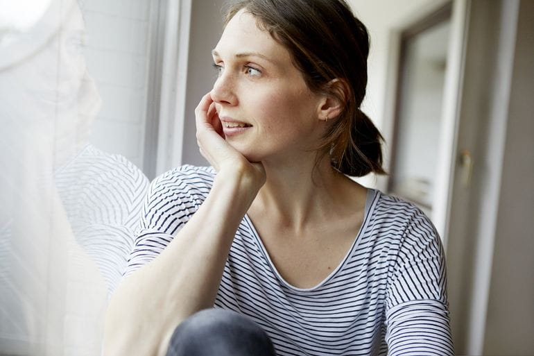 Une femme semble regarder par sa fenêtre.